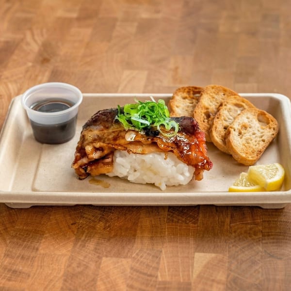 Grilled mackerel nigiri with green onions, soy sauce, toasted bread, and lemon wedges on a tray.