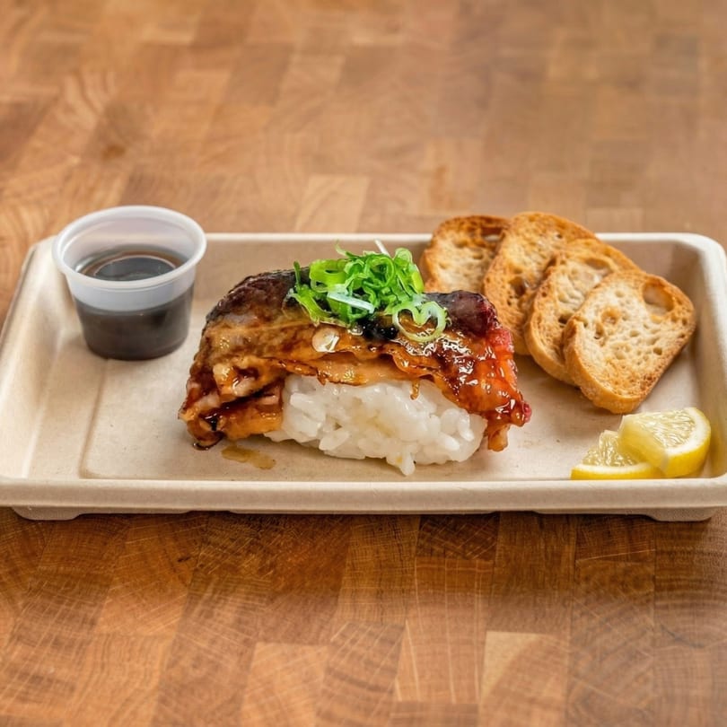 Grilled mackerel nigiri with green onions, soy sauce, toasted bread, and lemon wedges on a tray.