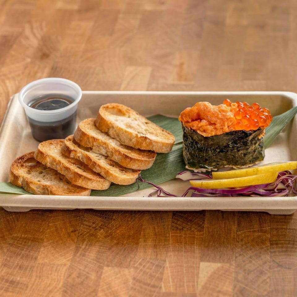 Uni and salmon roe gunkan maki with toasted bread, soy sauce, lemon, and red cabbage.